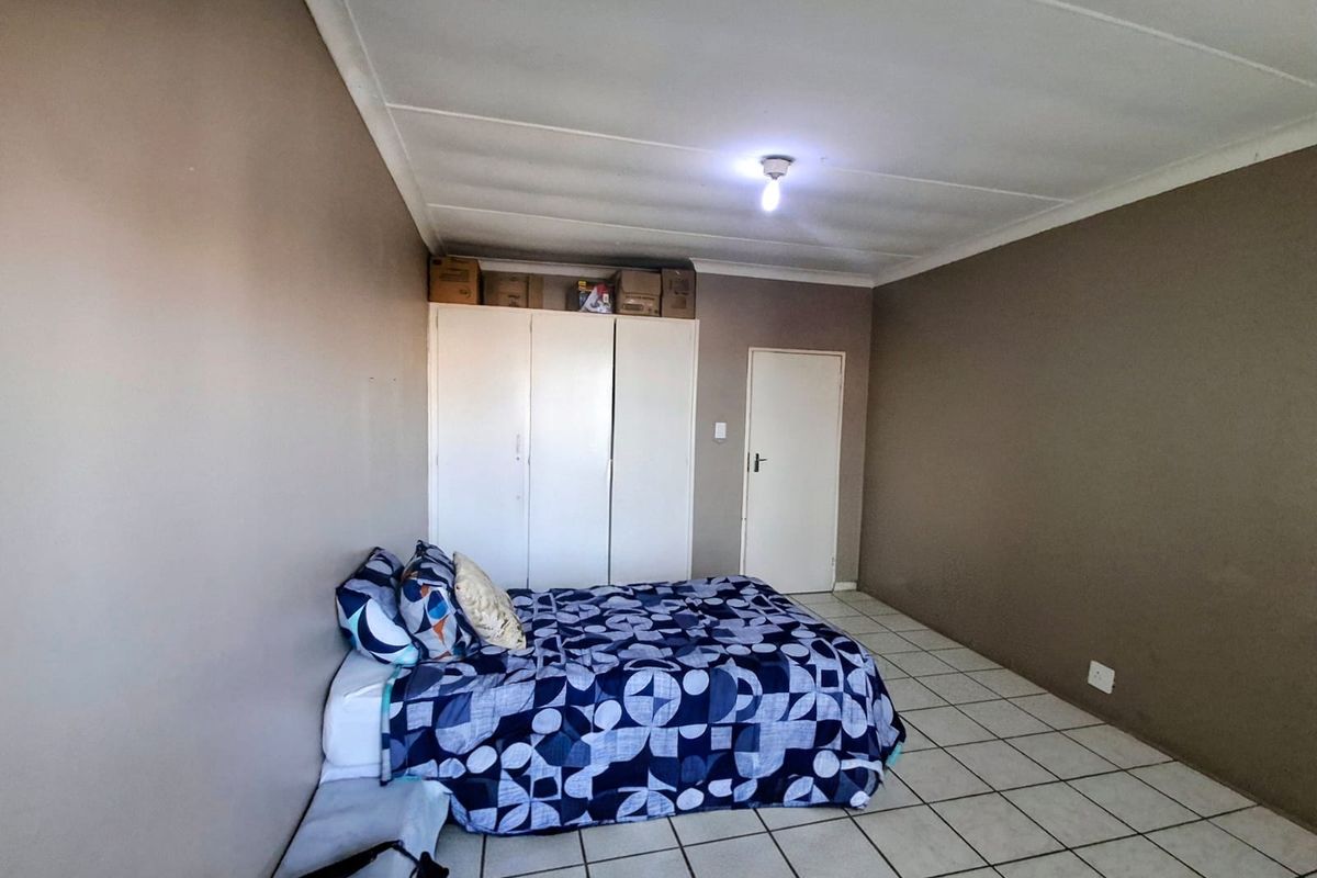 A bedroom featuring tiled flooring and built-in cupboards, offering a functional space with neutral wall tones.