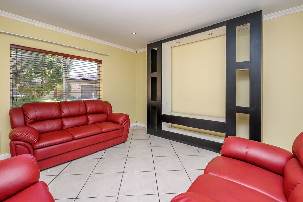 A living room featuring tiled flooring, recessed downlights, and a large built-in black shelving unit.