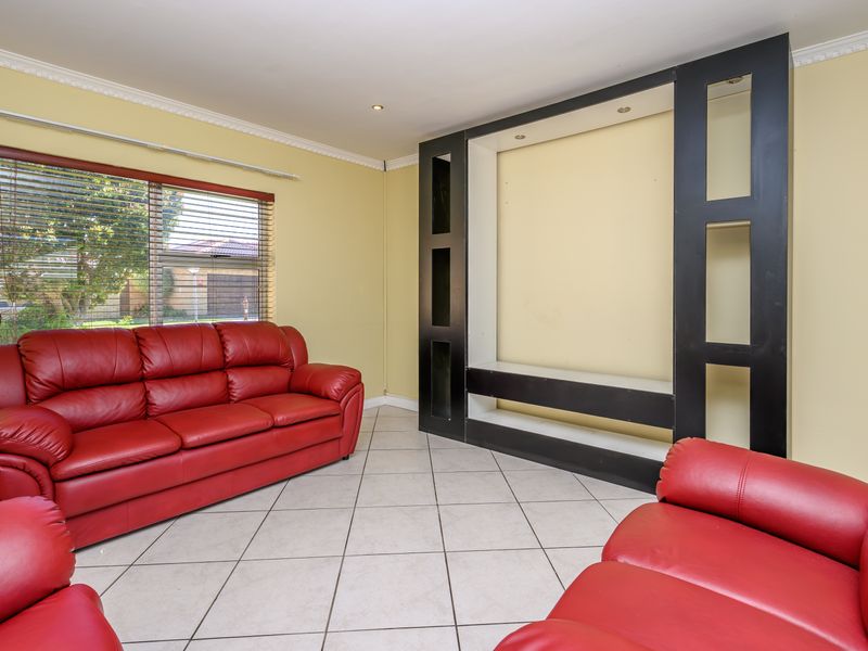 A living room featuring tiled flooring, recessed downlights, and a large built-in black shelving unit.