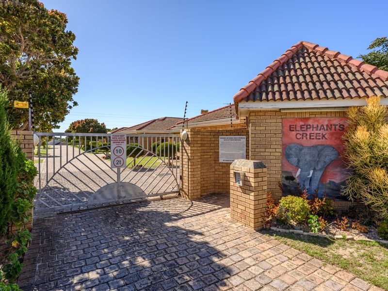 The entrance to Elephants Creek complex featuring a secure electric gate, brick boundary wall, and paved driveway access.