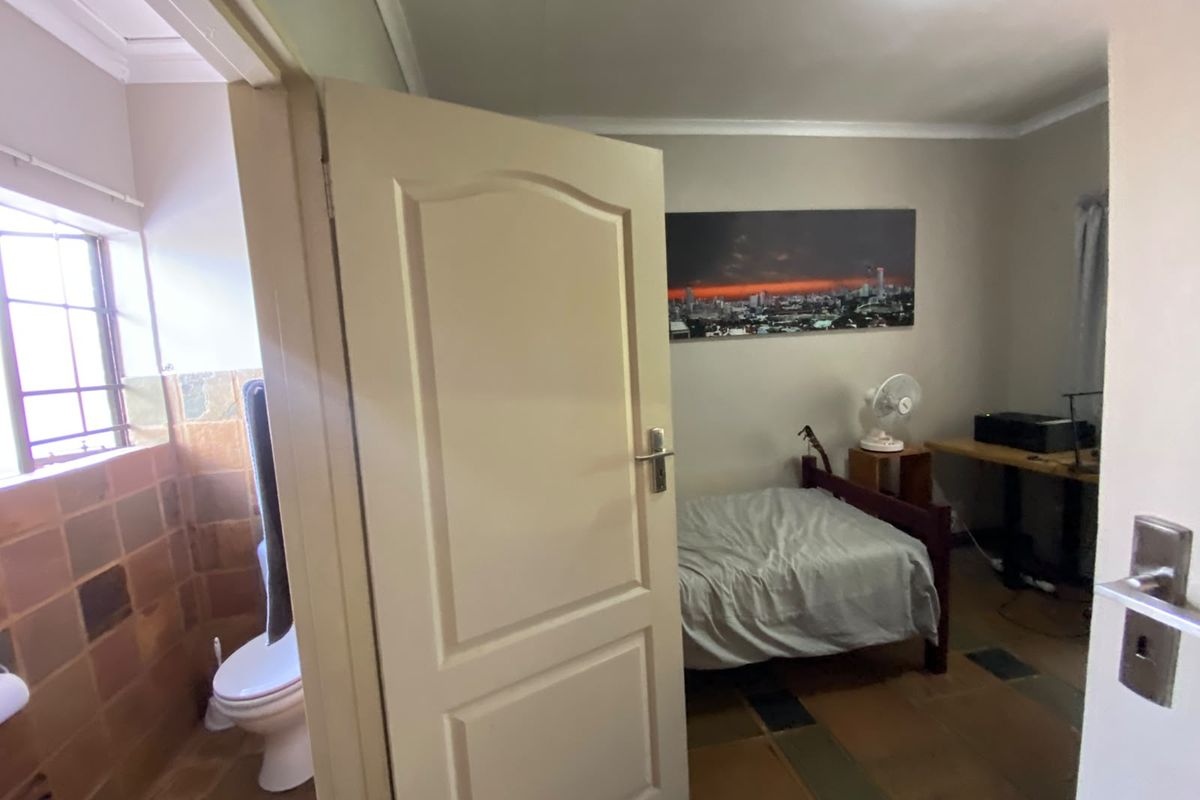 A bedroom featuring tiled flooring and coved ceiling, with an adjacent bathroom visible through the open doorway.