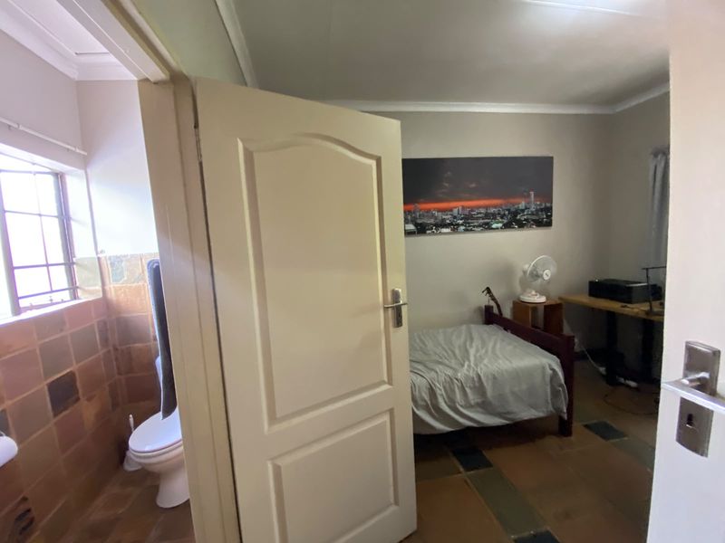 A bedroom featuring tiled flooring and coved ceiling, with an adjacent bathroom visible through the open doorway.