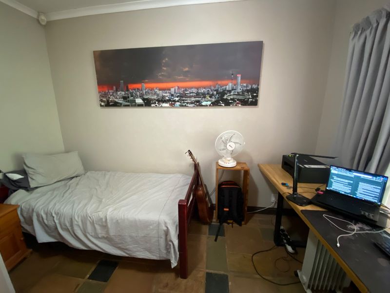 A functional bedroom featuring tiled flooring and neutral wall finishes, suitable for use as a guest room or home office.