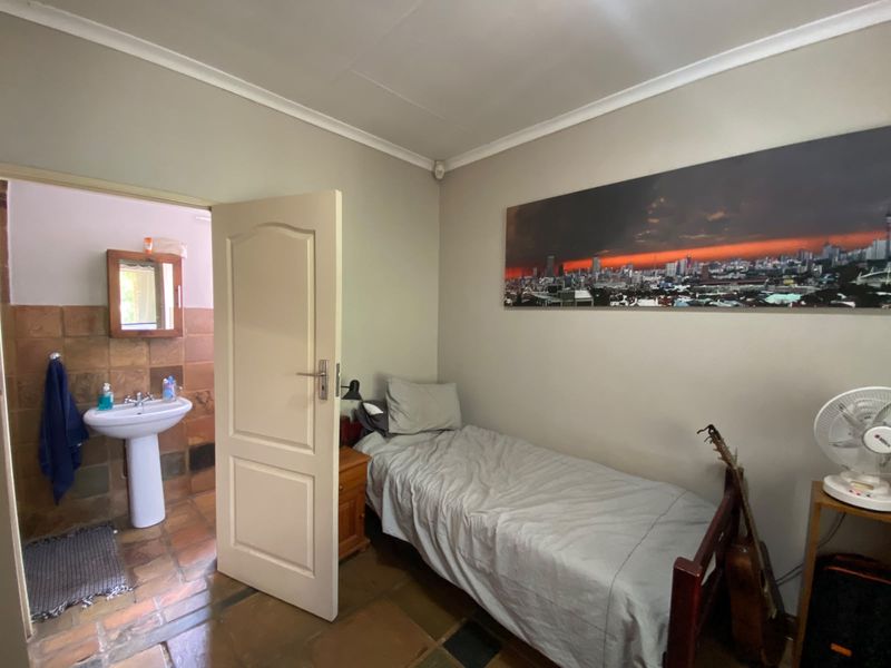 A bedroom featuring tiled flooring and coving, with an adjoining en-suite bathroom containing a pedestal basin.