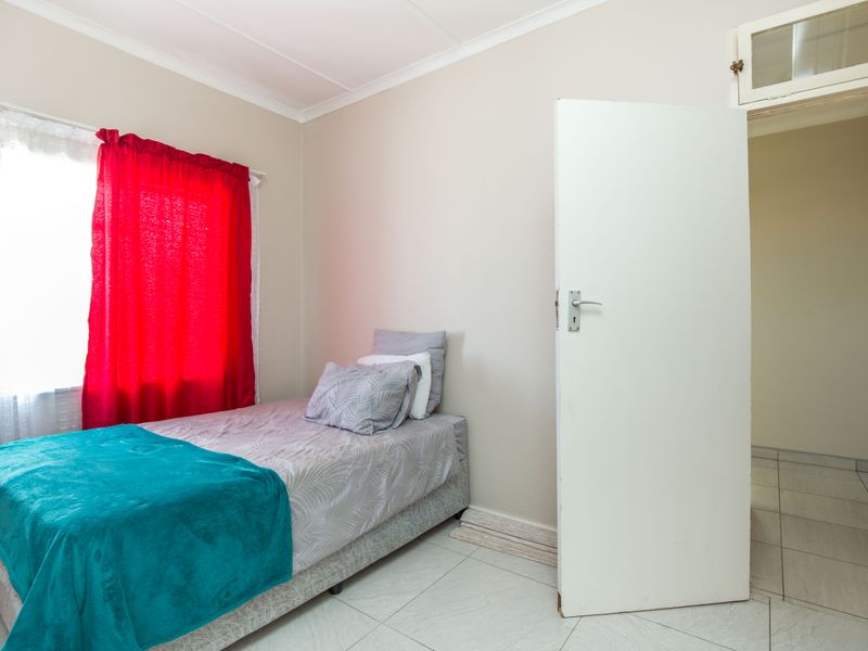 A functional bedroom featuring tiled flooring and a transom window above the doorway, providing a neutral base for personalization.