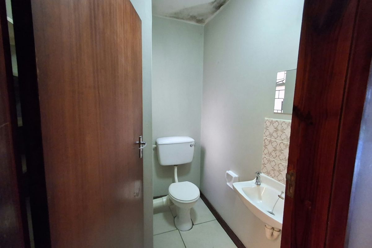A compact guest bathroom featuring a toilet and wall-mounted basin, currently showing signs of water damage on the ceiling requiring repair.