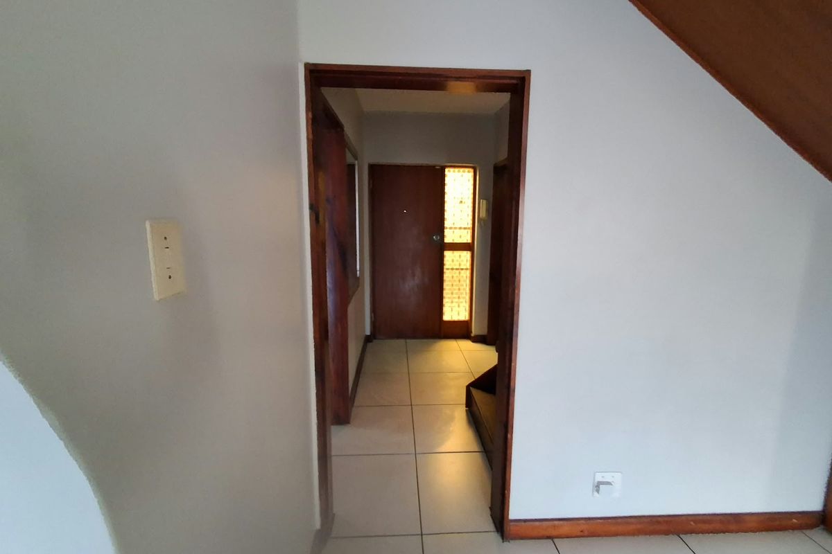 An entry hallway featuring tiled flooring and a timber door with a decorative glass panel, leading into the main living area.
