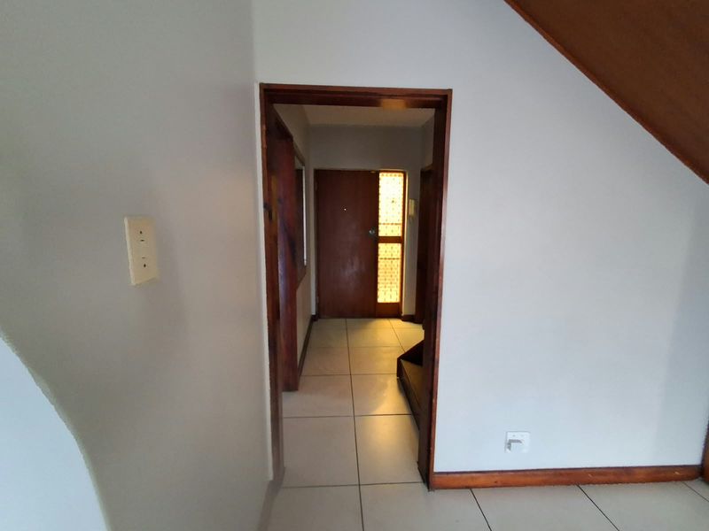 An entry hallway featuring tiled flooring and a timber door with a decorative glass panel, leading into the main living area.
