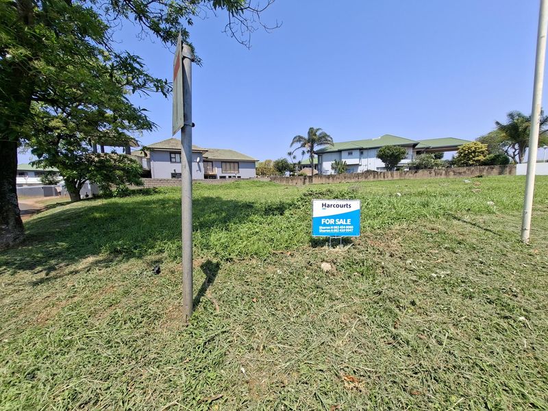 A vacant residential plot of land featuring a grass lawn and boundary wall, currently listed for sale.