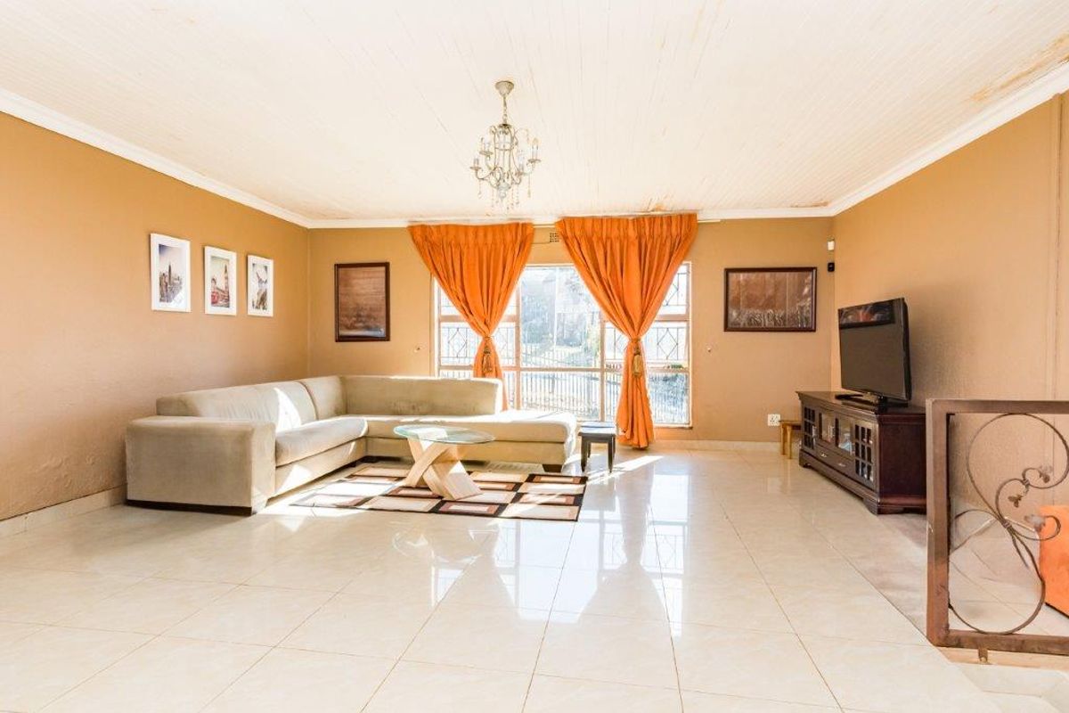 Spacious living room featuring polished tile flooring, a large window allowing natural light, and a classic ceiling chandelier.