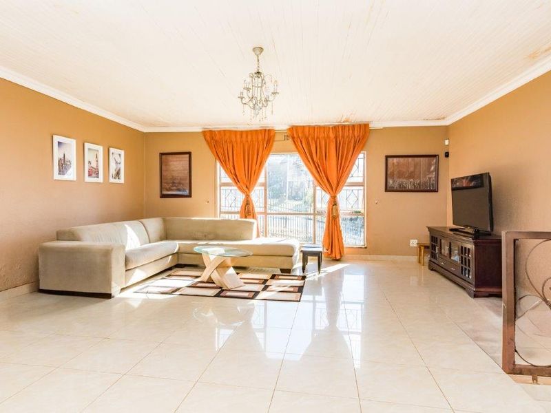 Spacious living room featuring polished tile flooring, a large window allowing natural light, and a classic ceiling chandelier.