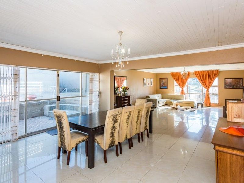 Spacious open-plan living and dining area featuring large sliding glass doors, tiled flooring, and a classic tongue and groove ceiling.