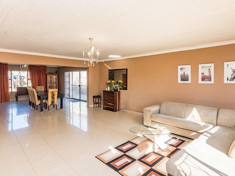 Spacious open-plan living and dining area featuring large format floor tiles, a classic tongue and groove ceiling, and direct access to the outdoor space.