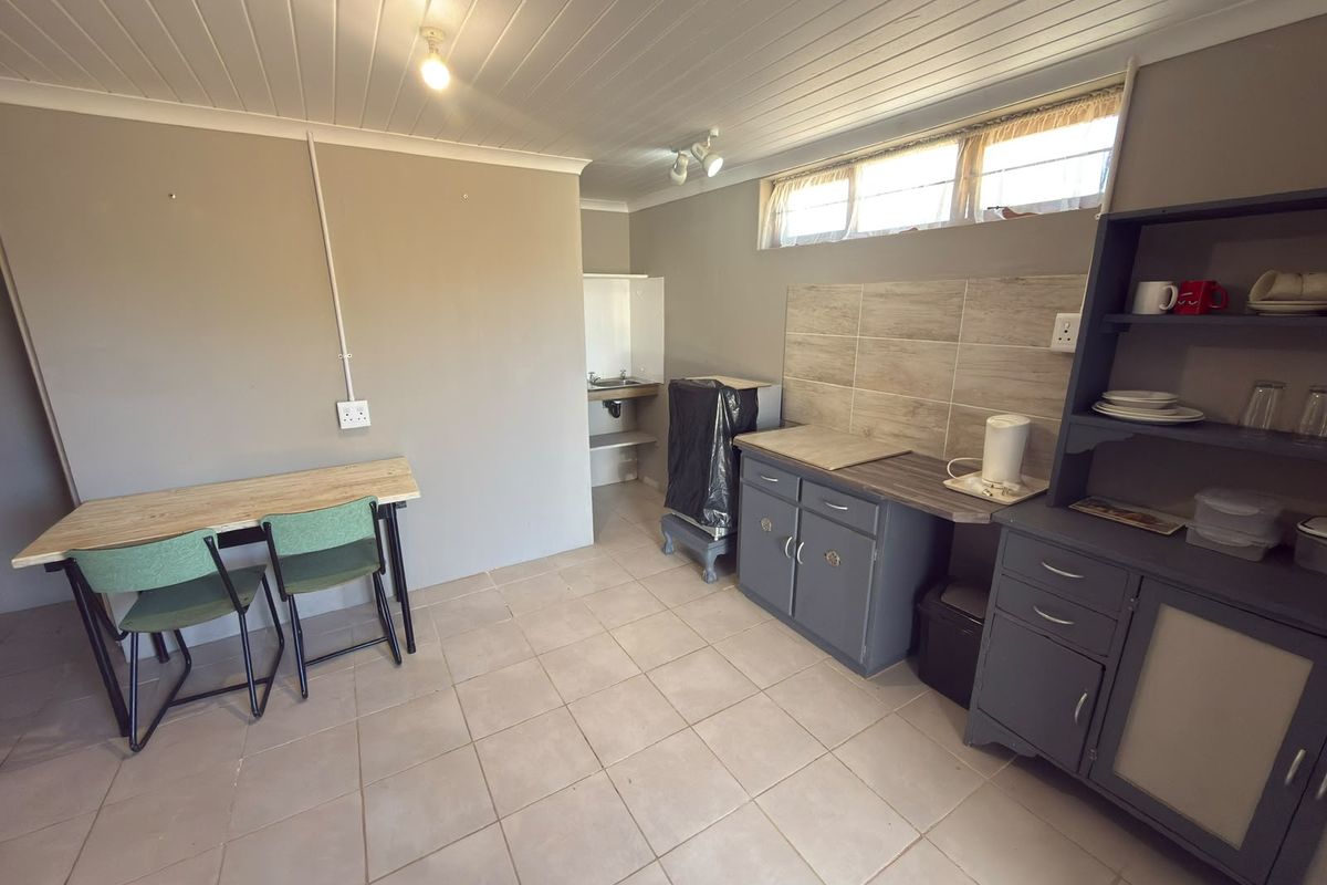 A functional kitchen area featuring tiled flooring, a tiled splashback, built-in cabinetry, and a sink, with a tongue and groove ceiling.