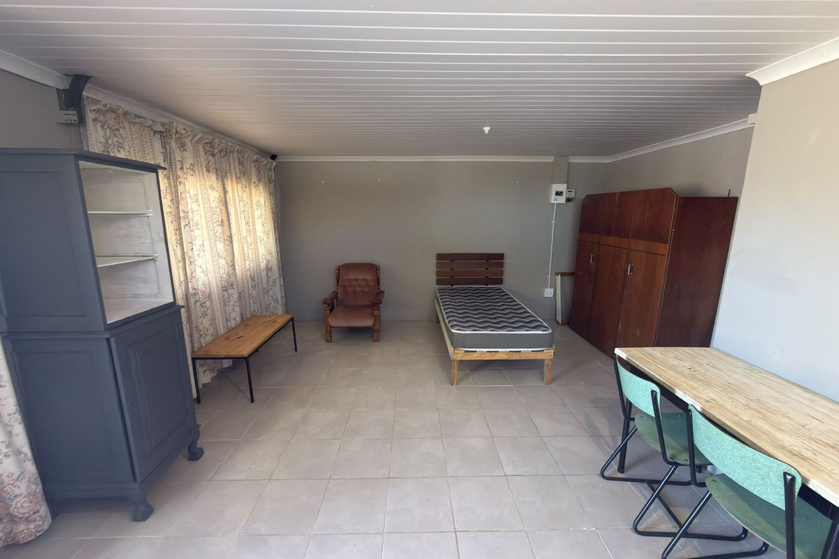 A spacious bedroom featuring tiled flooring and a tongue and groove ceiling, offering a functional layout with potential for modernization.