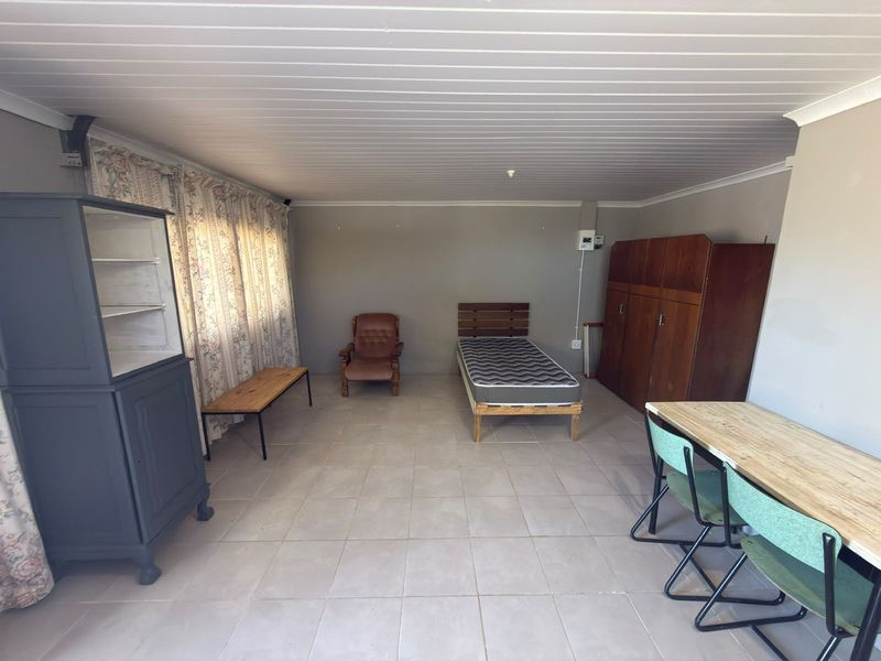 A spacious bedroom featuring tiled flooring and a tongue and groove ceiling, offering a functional layout with potential for modernization.