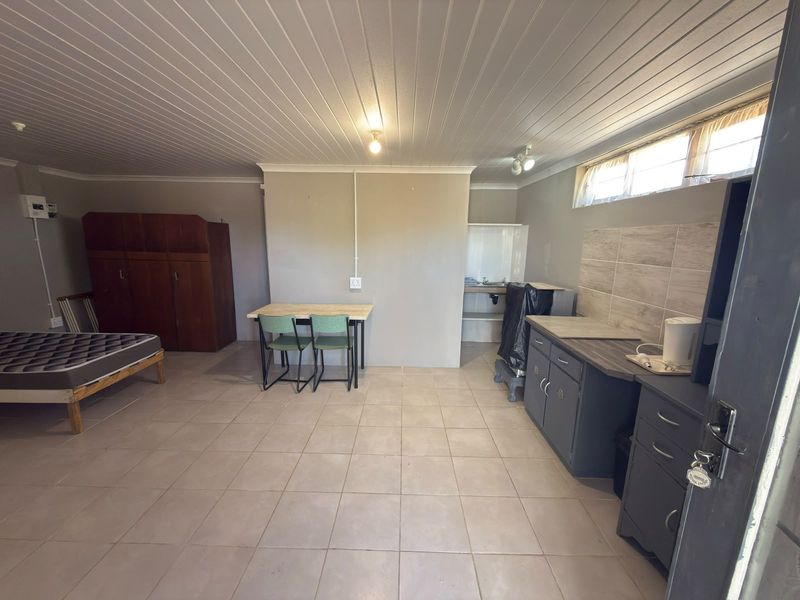 Open-plan living area featuring tiled flooring, a basic kitchenette with built-in cabinetry, and a tongue and groove ceiling.