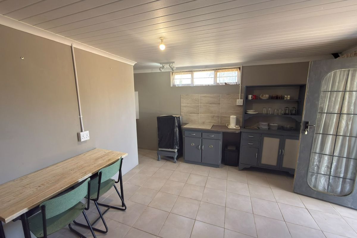 A functional kitchen area featuring built-in cabinetry, tiled backsplash, and tiled flooring, with a tongue and groove ceiling and horizontal window.