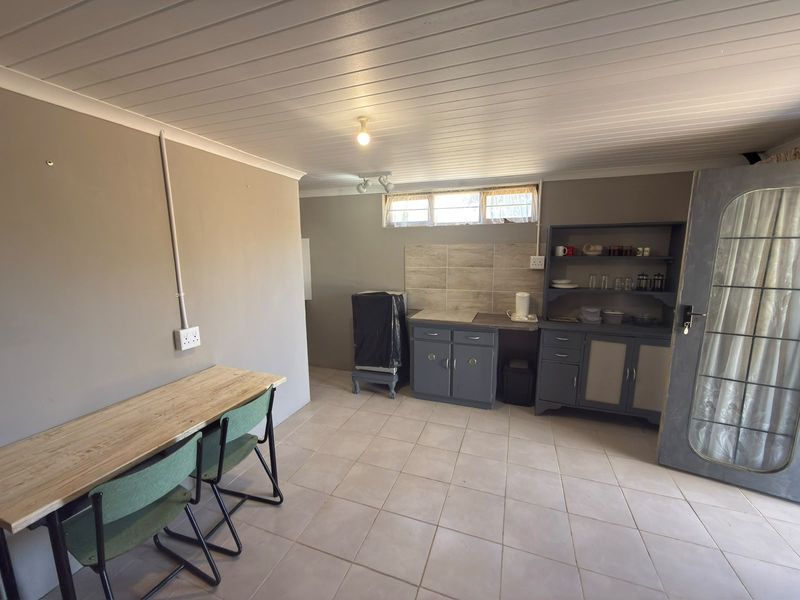 A functional kitchen area featuring built-in cabinetry, tiled backsplash, and tiled flooring, with a tongue and groove ceiling and horizontal window.