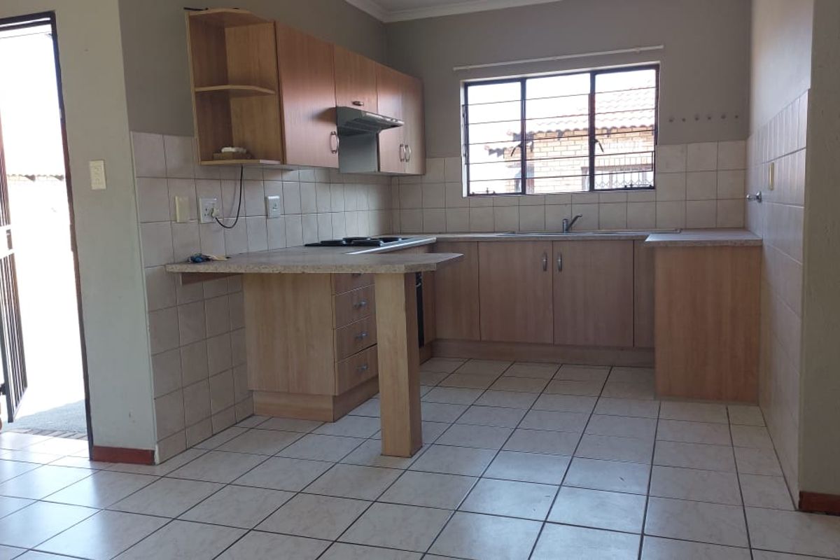 A functional kitchen featuring laminate cabinetry, built-in hob with extractor, and tiled flooring, offering a clean and practical layout for daily use.