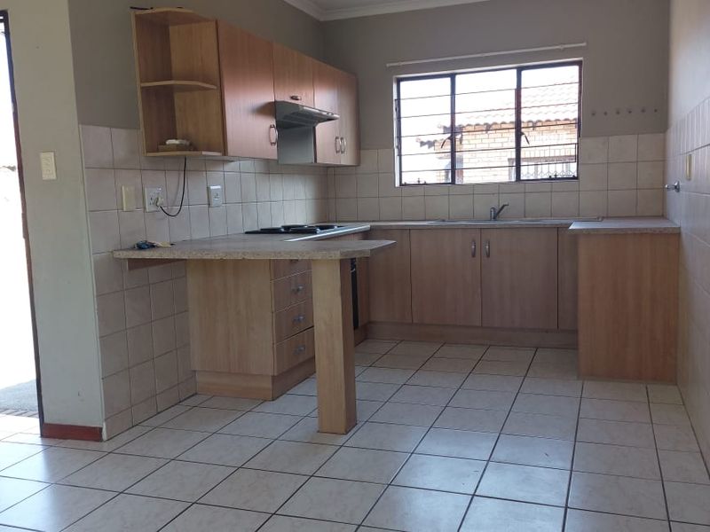 A functional kitchen featuring laminate cabinetry, built-in hob with extractor, and tiled flooring, offering a clean and practical layout for daily use.