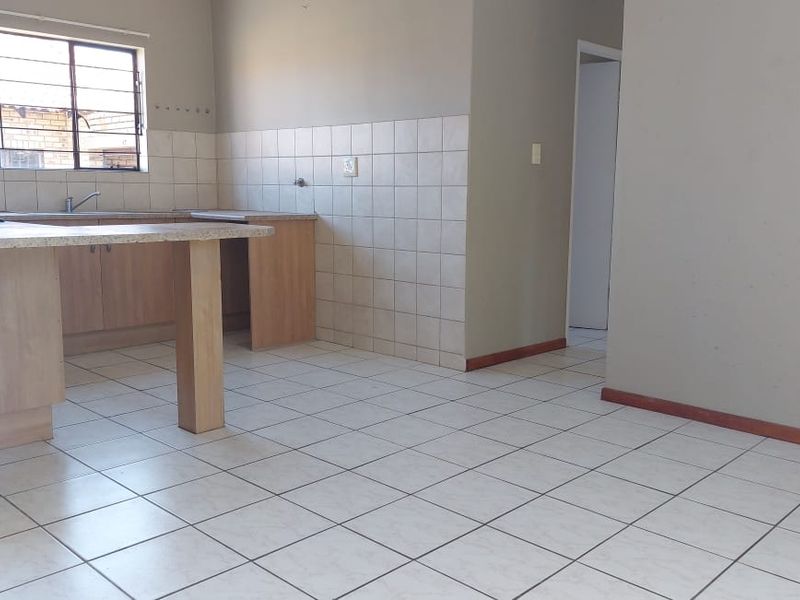Open plan kitchen and living area featuring tiled flooring, laminate cabinetry, and neutral wall finishes in a townhouse setting.