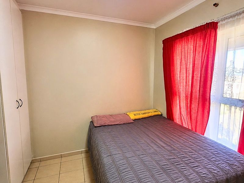 A functional bedroom featuring tiled flooring, a built-in wardrobe, and a ceiling light fixture, providing a practical living space.