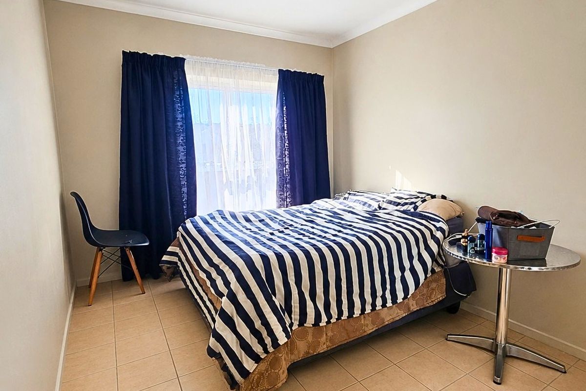 A functional bedroom featuring neutral wall tones, tiled flooring, and a coved cornice, providing a clean and simple living space.