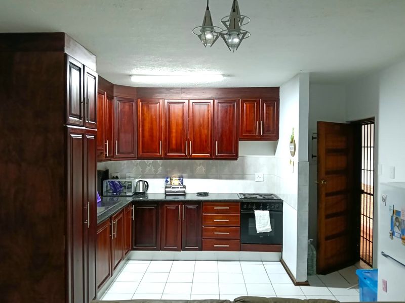 A functional kitchen featuring dark wood cabinetry, granite countertops, a built-in oven, and tiled flooring, offering a classic aesthetic with ample storage space.