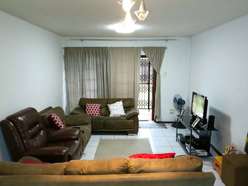 A living room featuring tiled flooring and a security gate leading to an outdoor area, providing a functional and accessible living space.