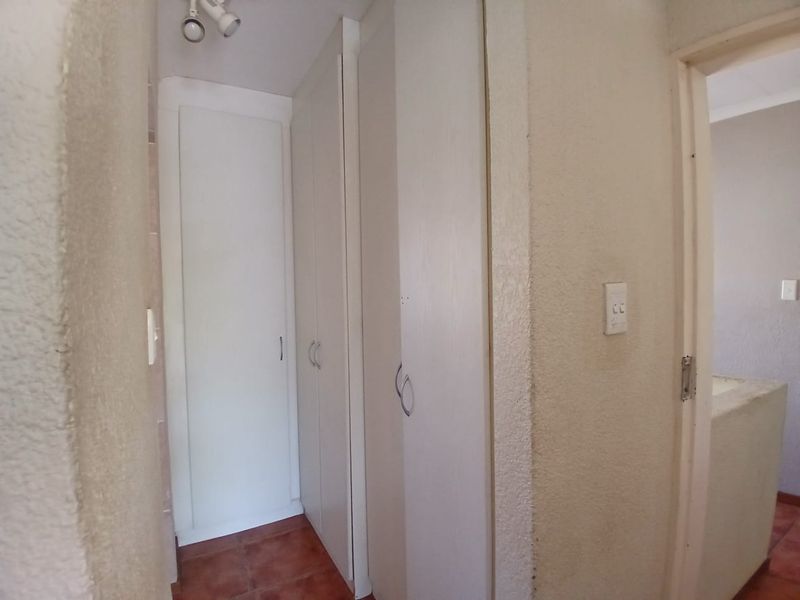 A functional hallway featuring built-in storage cupboards and tiled flooring, providing practical storage space within the apartment.