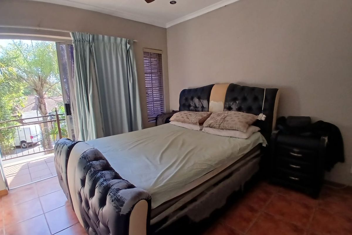 A bedroom featuring tiled flooring, a ceiling fan, and direct access to a private balcony through sliding glass doors.