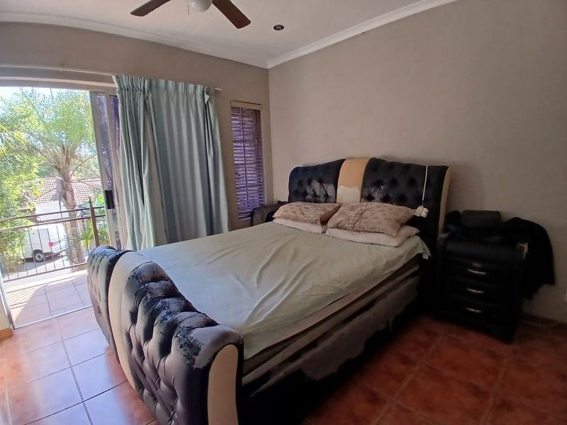 A bedroom featuring tiled flooring, a ceiling fan, and direct access to a private balcony through sliding glass doors.