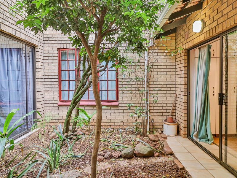 A private rear courtyard featuring face brick walls, sliding glass doors providing indoor-outdoor flow, and a landscaped garden bed.