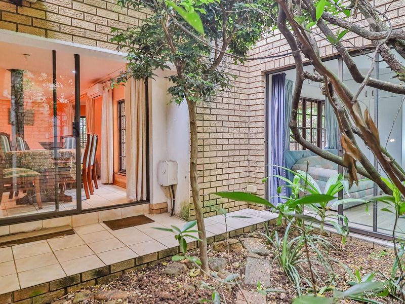 A paved patio area featuring facebrick walls and sliding glass doors providing access to the interior living spaces.