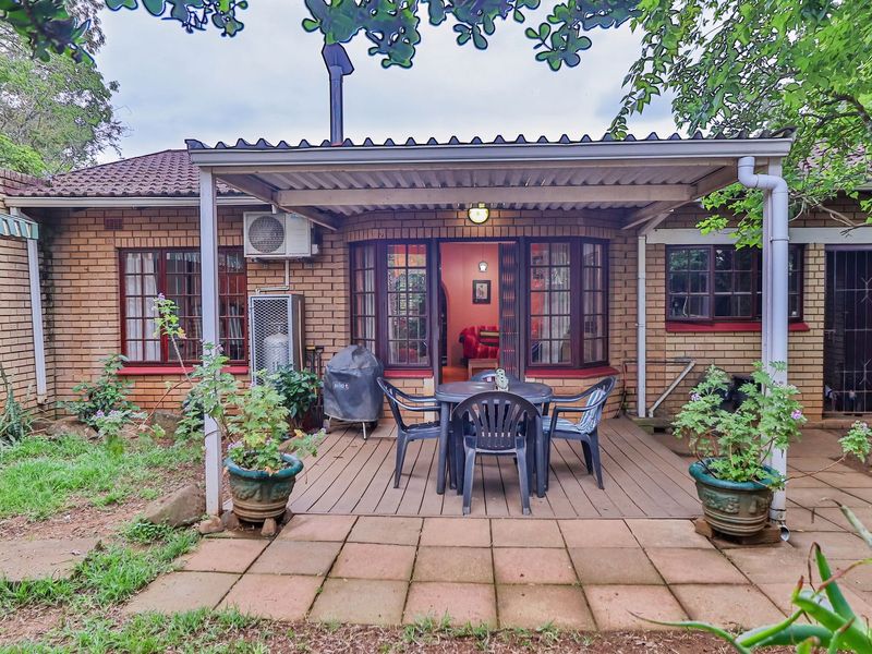 A covered patio area featuring brick exterior walls, timber decking, and paved flooring, providing a functional outdoor space for relaxation and entertainment.