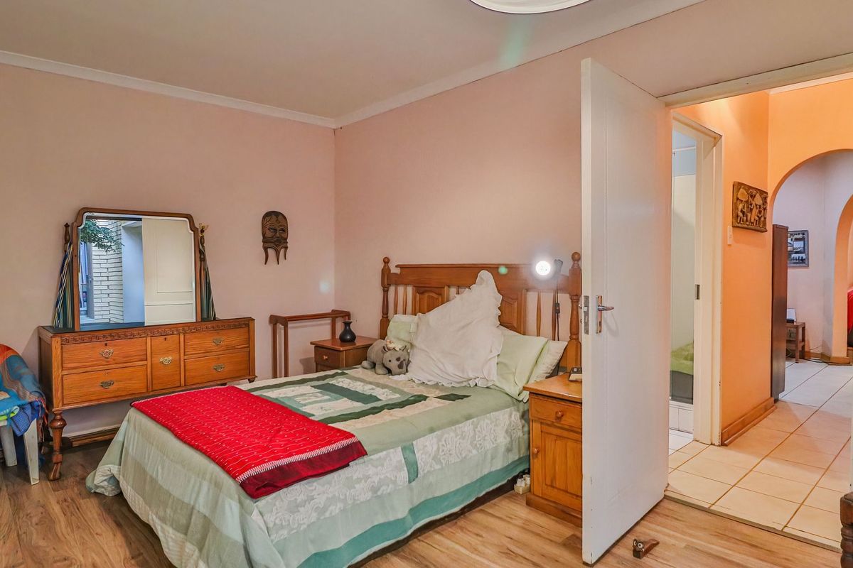 A standard bedroom featuring laminate flooring and access to an adjacent hallway, providing a functional living space with neutral wall finishes.