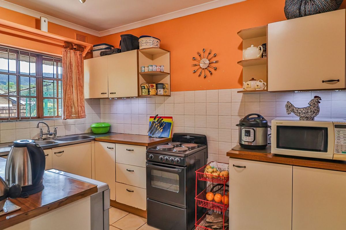 A functional kitchen featuring built-in cabinetry, laminate countertops, a stainless steel sink, and a tiled backsplash, offering a practical layout for daily meal preparation.