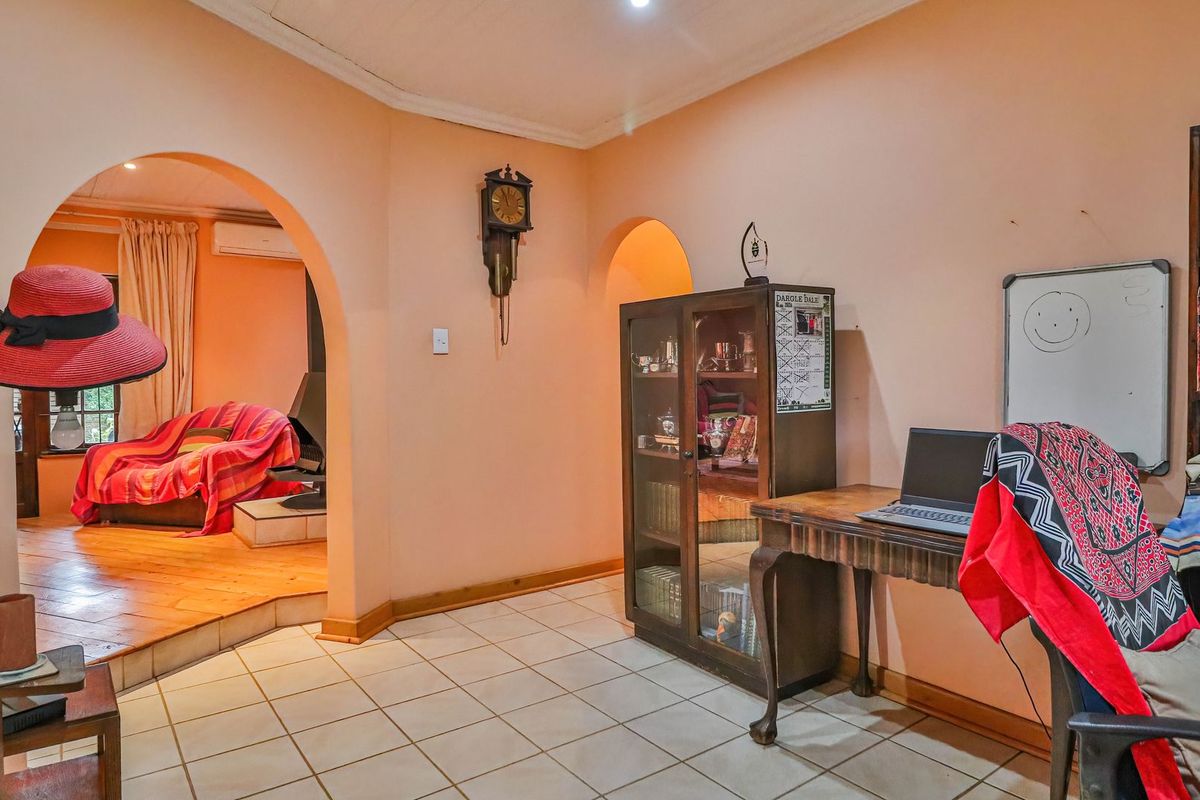 A living area featuring tiled flooring, arched doorways leading to an adjacent room, and built-in wall features with neutral wall tones.