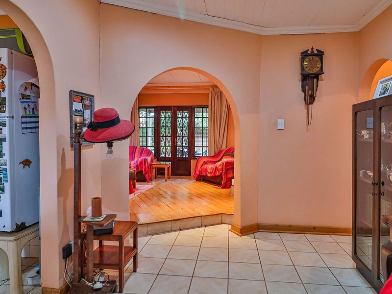 Open plan living area featuring arched architectural details, a mix of tiled and timber flooring, and access to the outdoor space through timber doors.