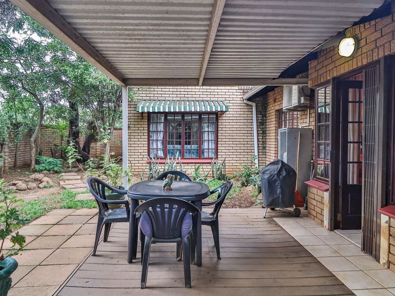 A covered patio area featuring a combination of timber decking and tiled flooring, providing direct access to the garden and main living area.