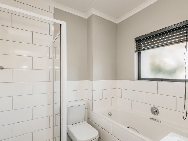 A clean, modern bathroom featuring a glass-enclosed shower, a built-in bathtub, and classic white subway tile wall finishes.