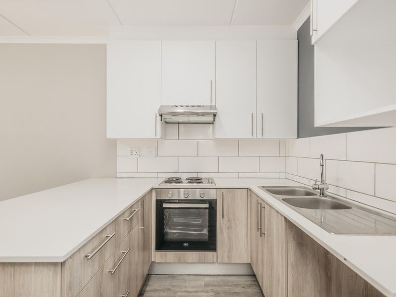 Modern kitchen featuring light wood-grain cabinetry, white quartz countertops, subway tile backsplash, and integrated stainless steel appliances.