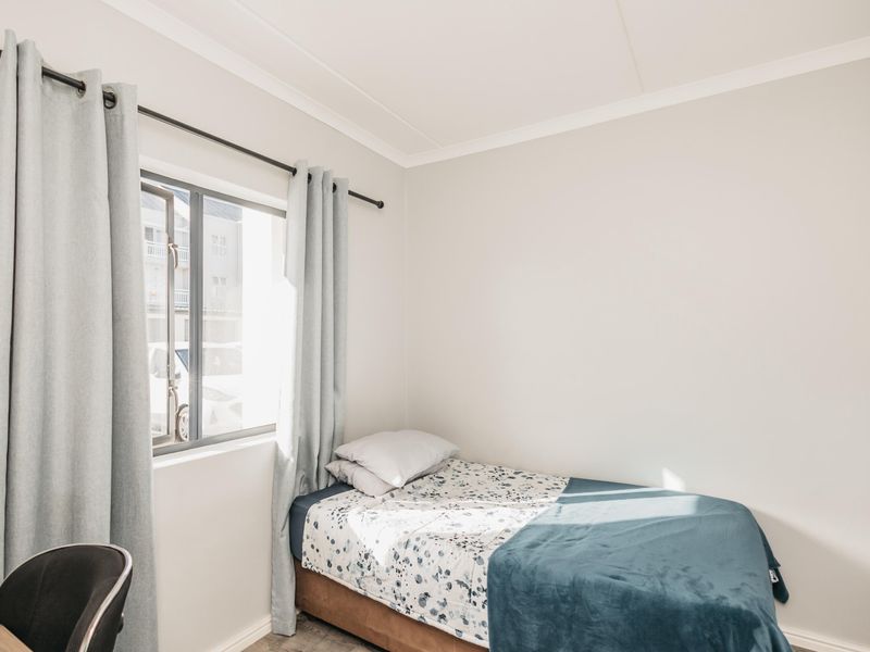 A bright and well-maintained bedroom featuring a window with natural light and a built-in cupboard for storage.