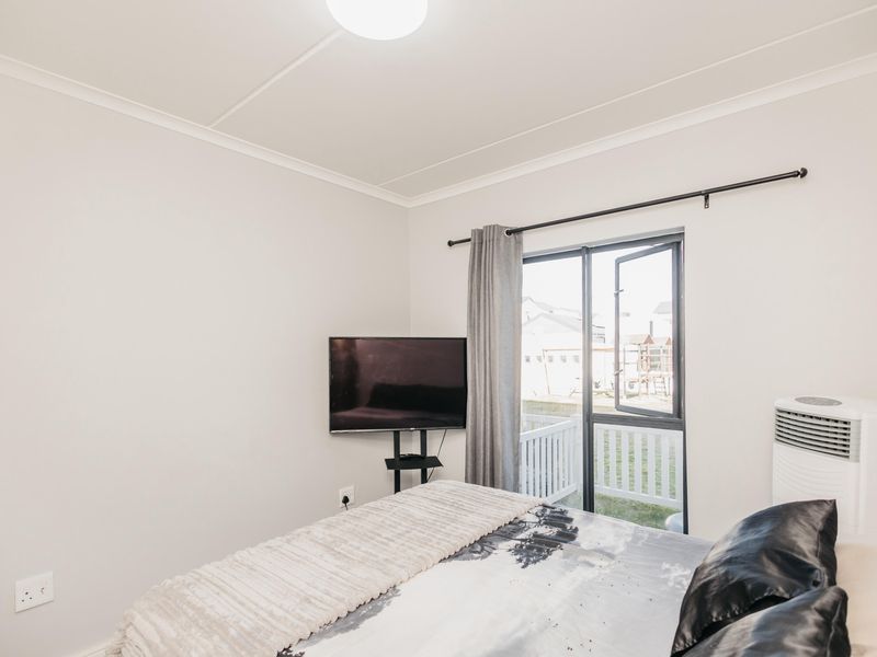 A bright bedroom featuring a sliding glass door that opens to a balcony, providing natural light and access to the outdoors.