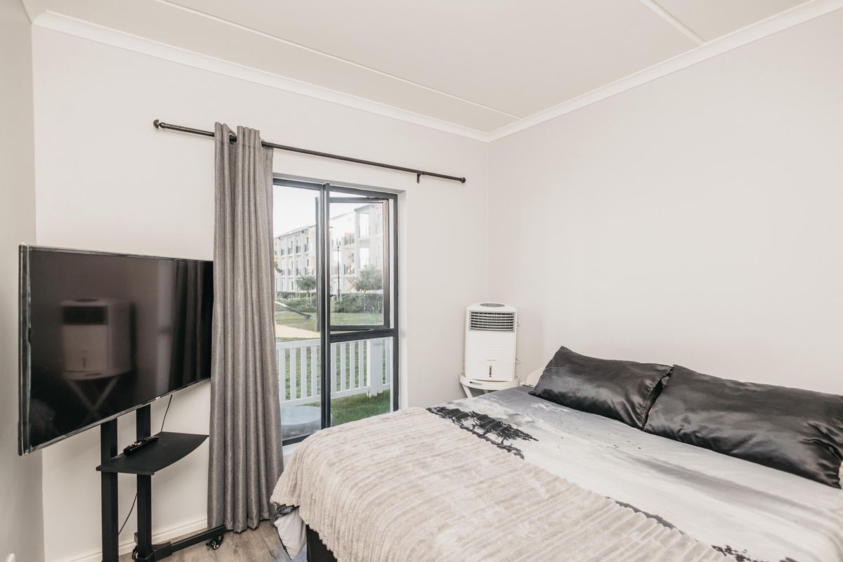 A well-lit bedroom featuring a sliding glass door with access to an outdoor area and neutral wall finishes.