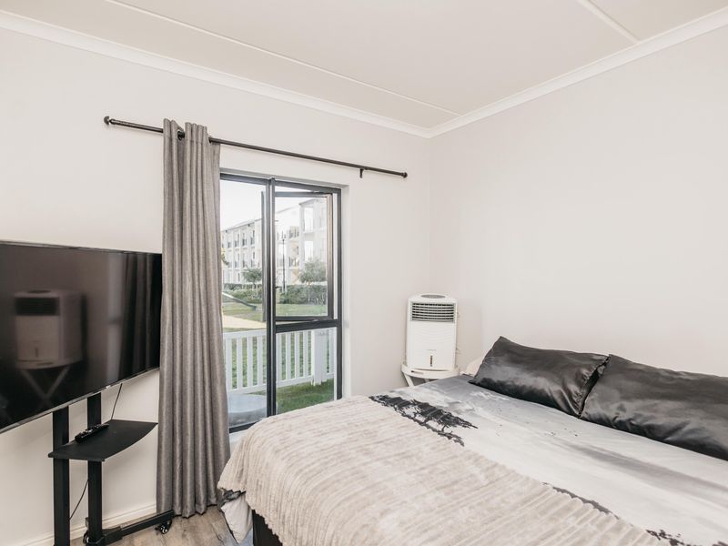 A well-lit bedroom featuring a sliding glass door with access to an outdoor area and neutral wall finishes.