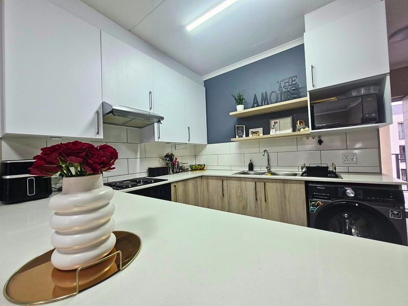Modern kitchen featuring white and wood-look cabinetry, subway tile backsplash, integrated appliances, and floating shelves, offering a clean and functional cooking space.