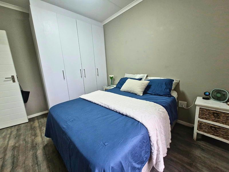 A well-maintained bedroom featuring built-in wardrobes, modern laminate flooring, and neutral wall finishes, providing a comfortable and functional living space.