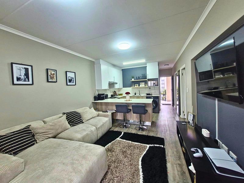 Open-plan living area featuring a modern kitchen with built-in cabinetry, a breakfast island, and laminate flooring throughout the combined space.